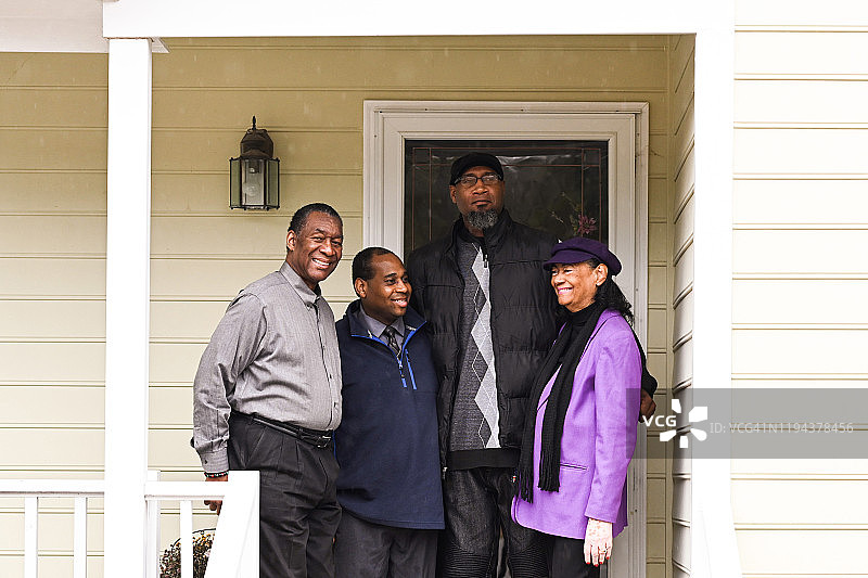 和两个儿子及丈夫在她家门廊上的中年妇女图片素材