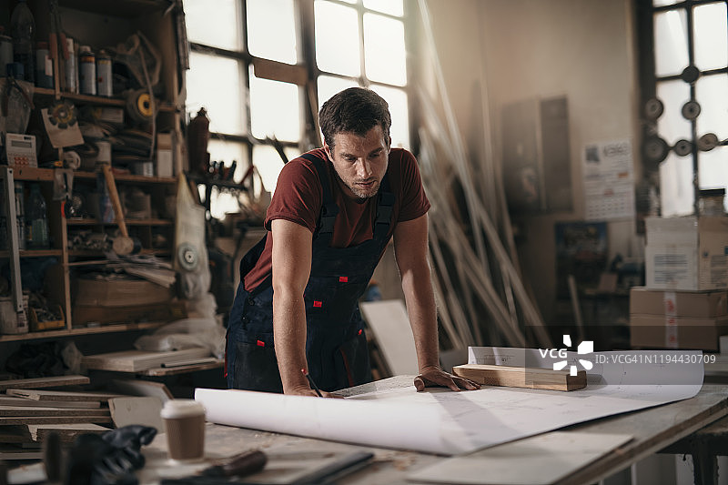 年轻木匠在车间制作家具时分析设计方案图片素材