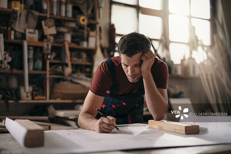 年轻木匠在车间制作家具时分析设计方案图片素材