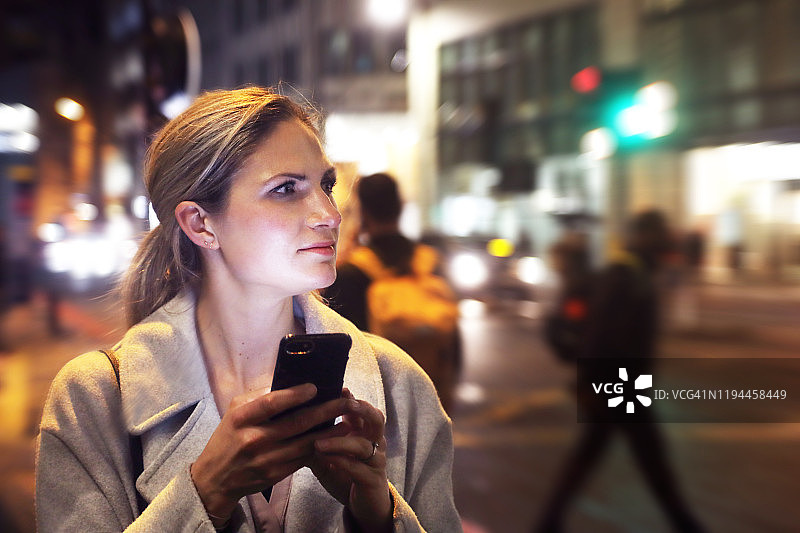 夜晚在城市里使用手机的女士图片素材