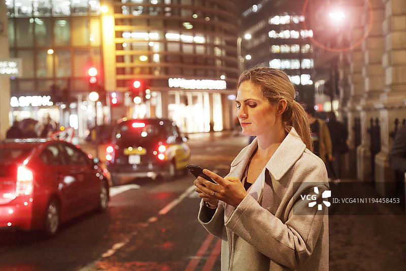 夜晚在城市里使用手机的女士图片素材