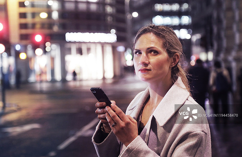 夜晚在城市里使用手机的女士图片素材
