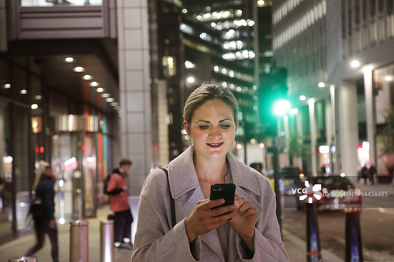 夜晚在城市里使用手机的女士图片素材
