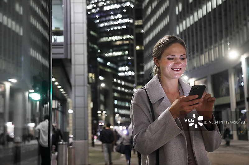 夜晚在城市里使用手机的女士图片素材