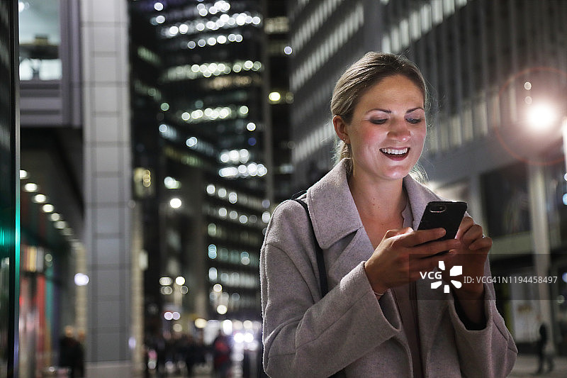 夜晚在城市里使用手机的女士图片素材