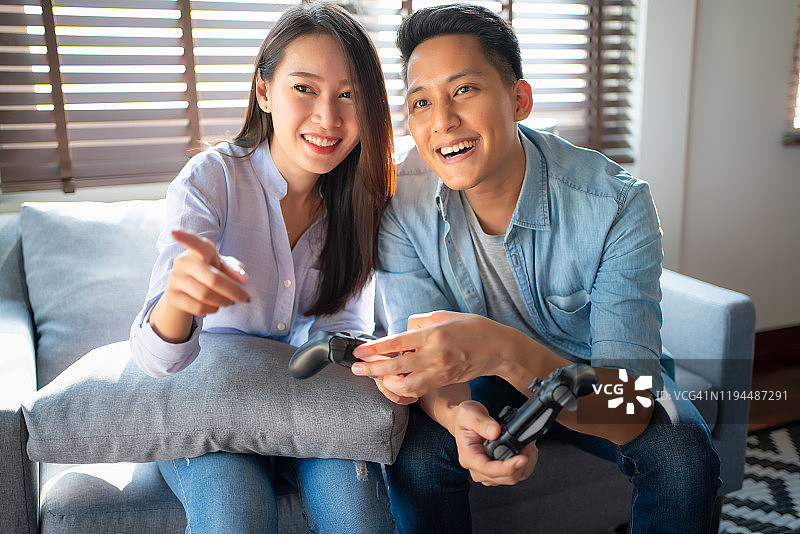 快乐的亚洲夫妇在客厅玩电子游戏图片素材
