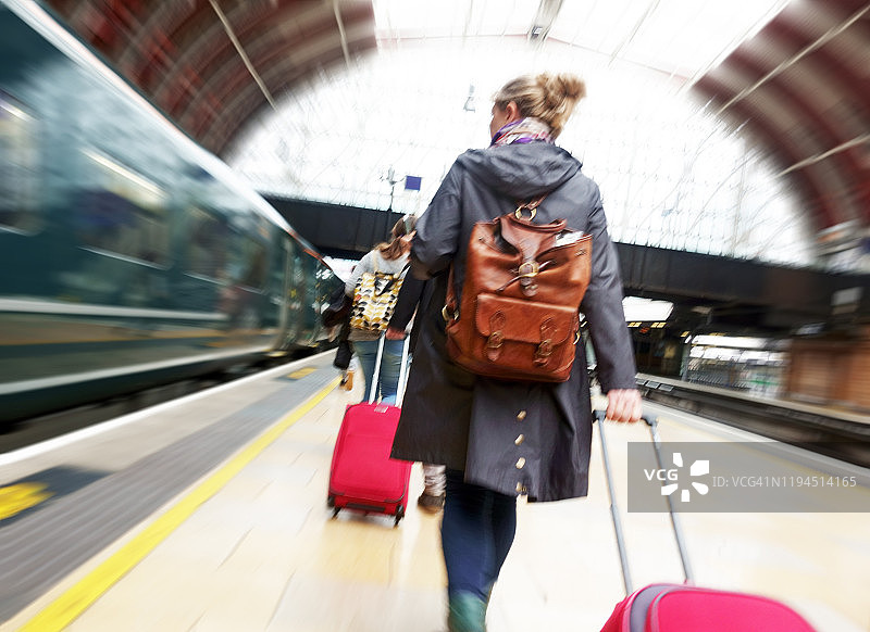 拖着行李箱走在火车站站台上的女人图片素材