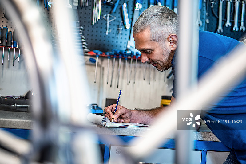 自行车修理工在他的清单笔记本上书写图片素材