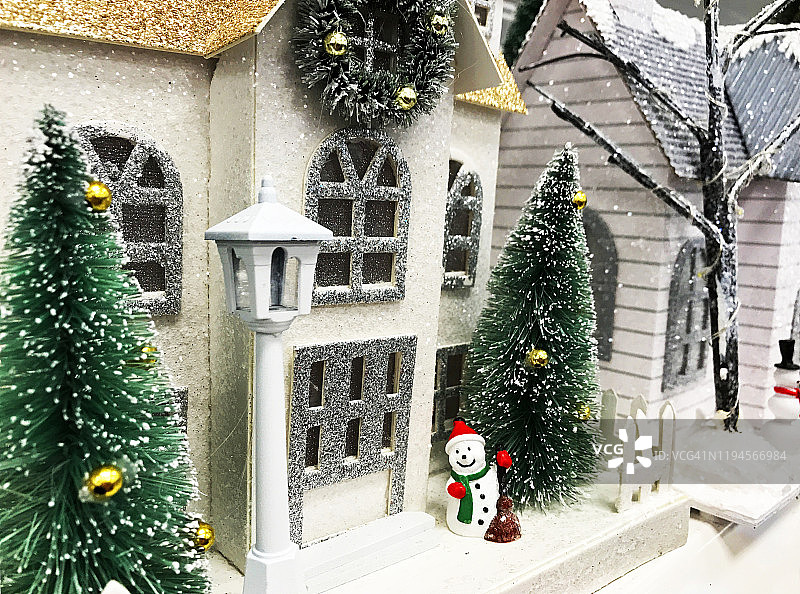 冬季场景中的圣诞房屋工艺品零售展示：雪人和松树图片素材