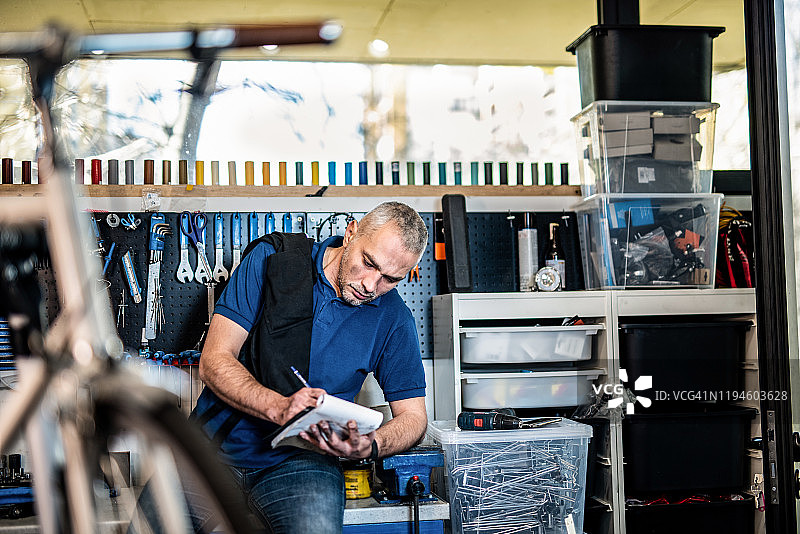 自行车修理工在他的清单笔记本上书写图片素材