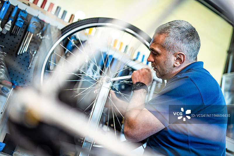 自行车修理工在工作间修理自行车车轮图片素材