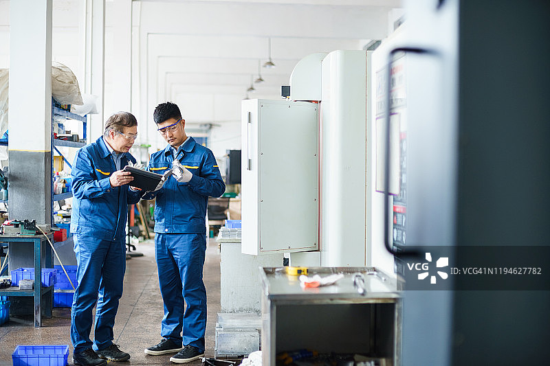 工程师在工厂使用数控车床和数字平板电脑图片素材