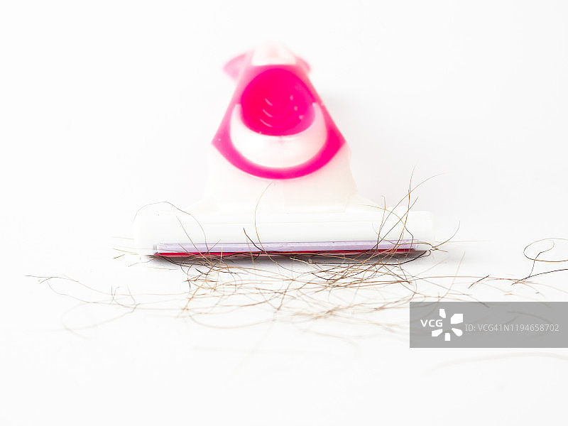 白色背景上沾有毛发的粉色一次性剃须刀特写图片素材
