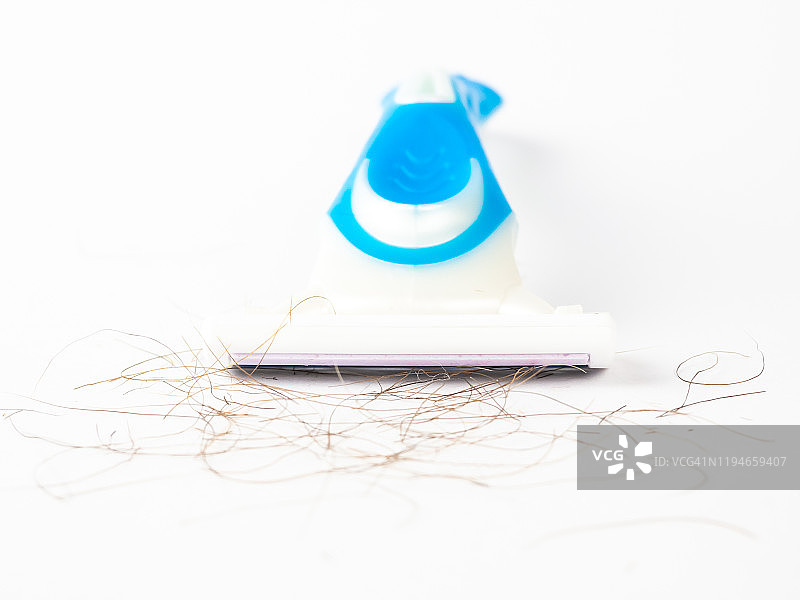 白色背景上刀片之间有毛发的蓝色一次性剃须刀特写图片素材