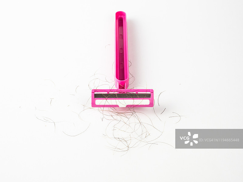 白色背景上沾有毛发的粉色一次性剃须刀特写图片素材