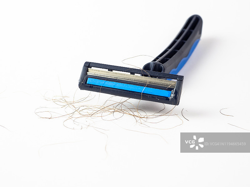 白色背景上刀片之间有毛发的蓝色一次性剃须刀特写图片素材