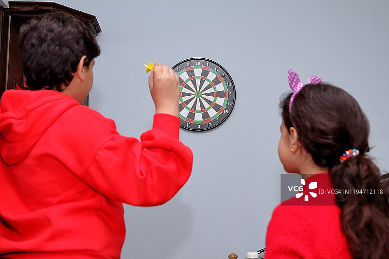 兄妹在房间里玩飞镖游戏图片素材