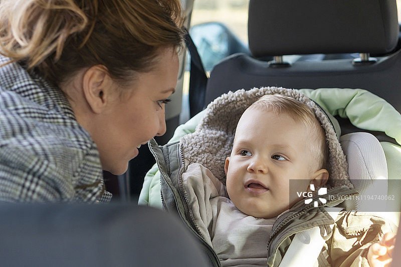 年轻妈妈安置男婴入汽车安全座椅图片素材