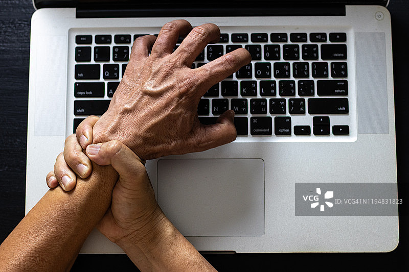 男人手腕手臂疼痛，使用笔记本电脑工作。办公室综合征医疗保健概念图片素材