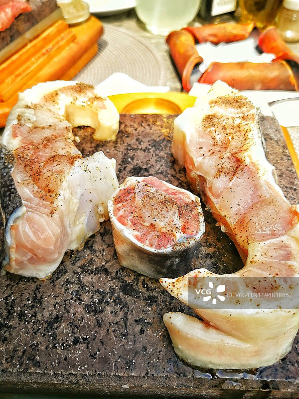 新鲜的鲟鱼配以调味料和香料，淋上橄榄油，在石板上烤制，特写图片素材