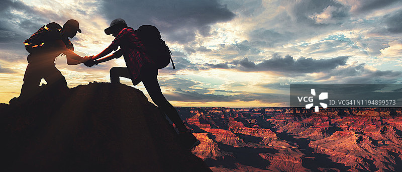 在山顶互相帮助攀登的亚洲年轻登山情侣图片素材
