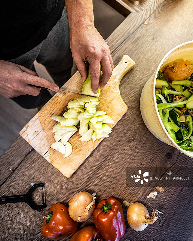 年轻男人在厨房台面砧板上切西葫芦图片素材