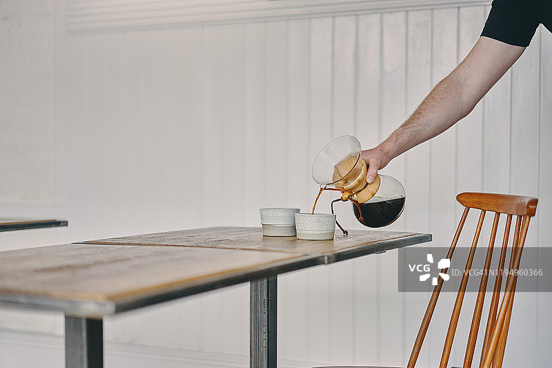 服务员在餐厅往桌上的杯子里倒咖啡图片素材