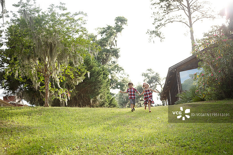 朝着相机跑来的小男孩和小女孩图片素材