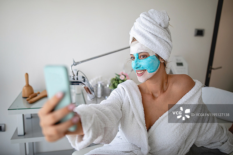 年轻女子敷着面膜用手机自拍图片素材