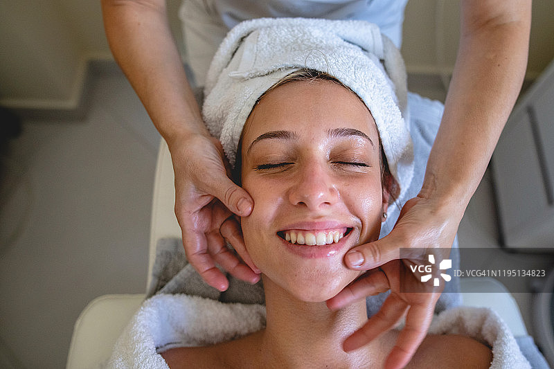 年轻女子在水疗中心享受面部按摩图片素材