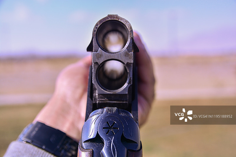 一名男子在飞碟射击场手持双管霰弹枪瞄准目标图片素材