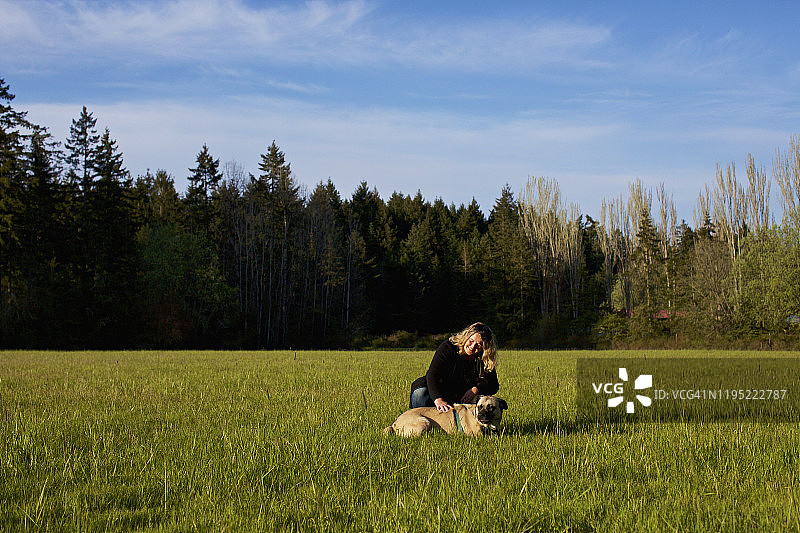 与狗在阳光明媚的乡村田野上的女人图片素材