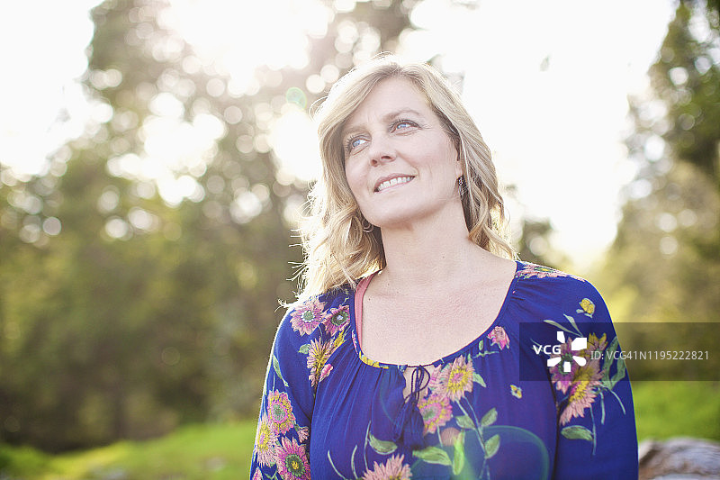 阳光明媚的公园里，面带微笑、神情平静的女子肖像图片素材