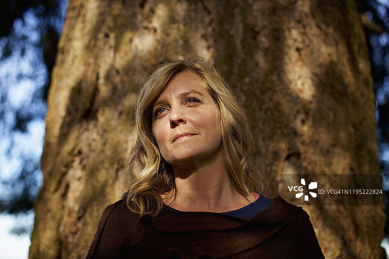 阳光明媚的树干旁宁静的女人肖像图片素材