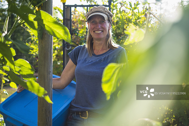 阳光明媚的菜园里自信微笑的农民肖像图片素材