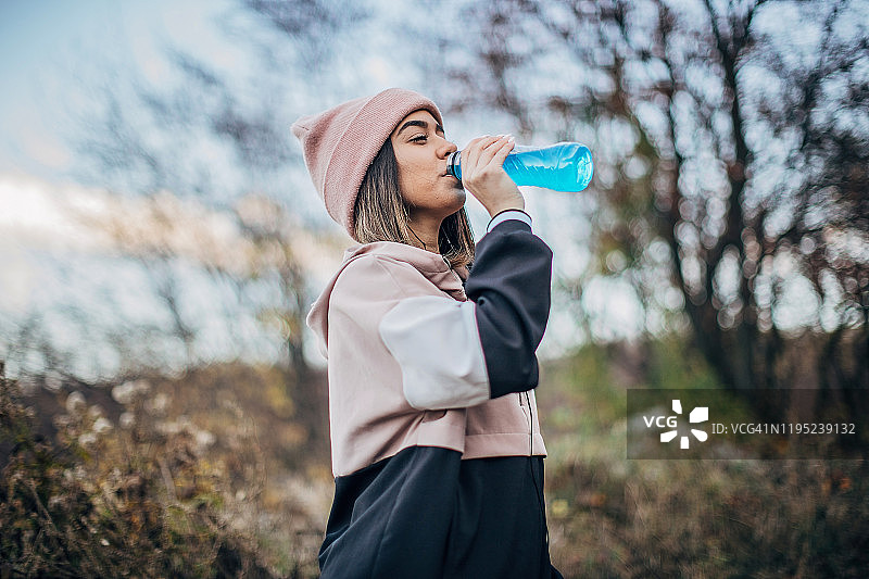 正在饮用能量饮料的年轻漂亮女人图片素材