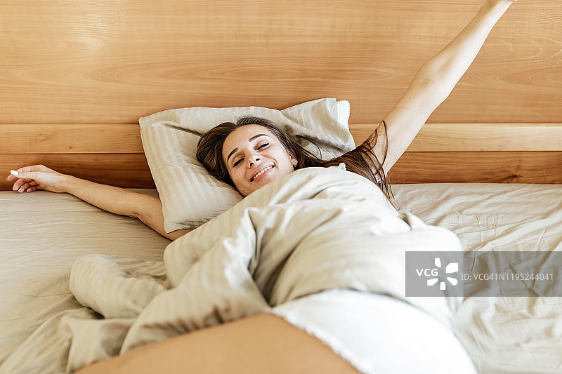 在卧室里伸展身体的年轻女人图片素材