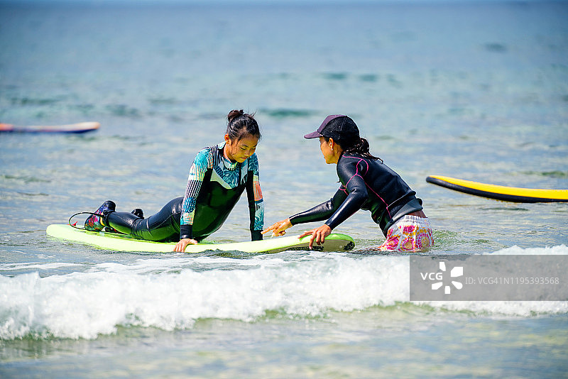 少女在母亲的指导下学习冲浪图片素材