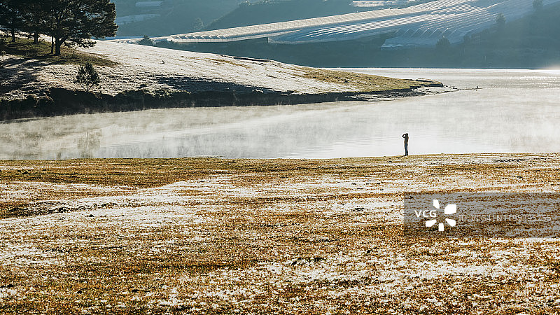 在雾气笼罩的湖边，与孤独的女子在草地上嬉戏图片素材
