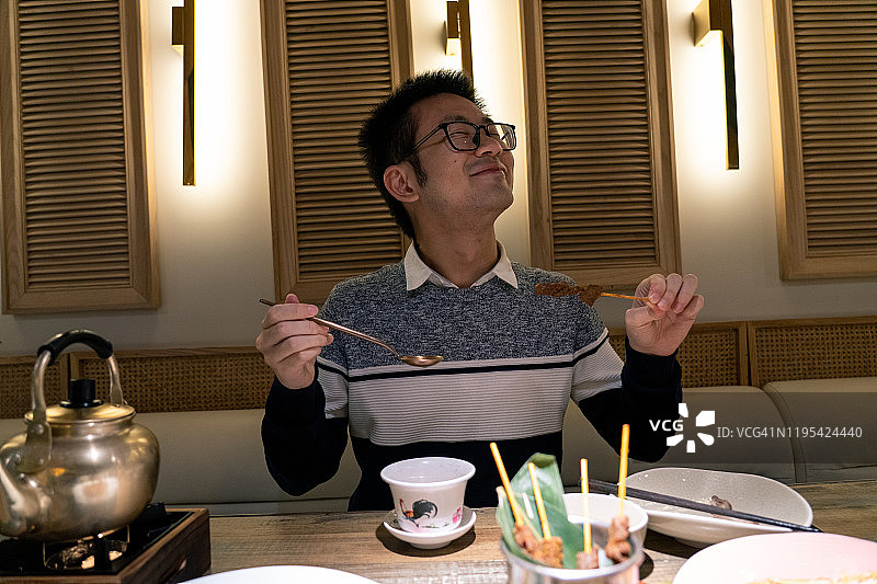 一位年轻的新加坡男人在一家餐厅吃新加坡美食图片素材