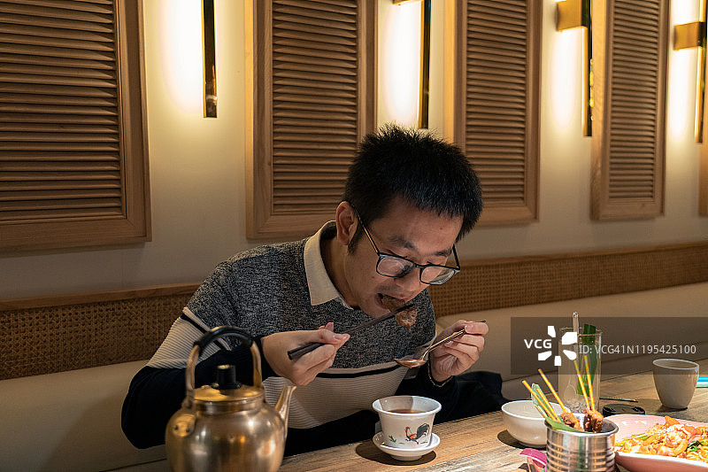 一位年轻的新加坡男人在一家餐厅吃新加坡美食图片素材