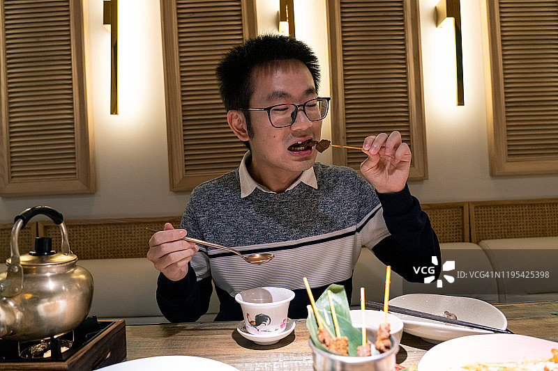 一位年轻的新加坡男人在一家餐厅吃新加坡美食图片素材