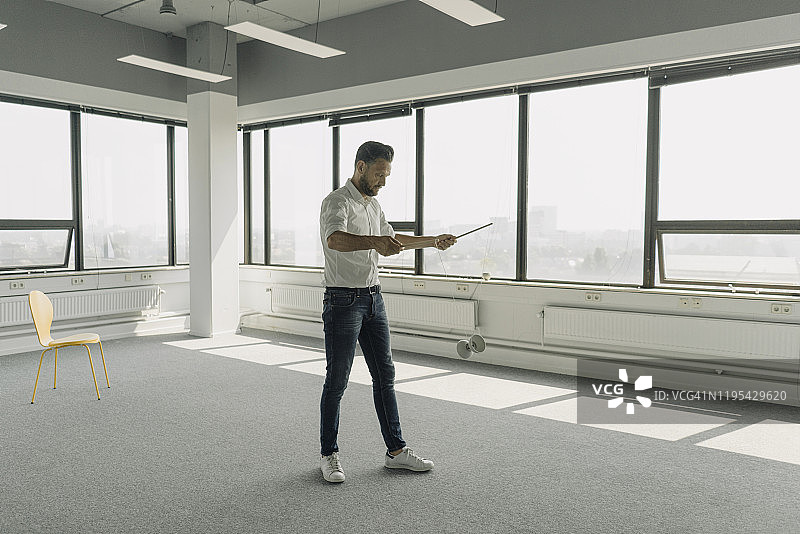 在空荡荡的办公室玩空竹的中年商人图片素材