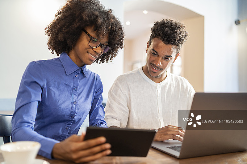 学生在咖啡馆使用笔记本电脑和平板电脑完成项目图片素材