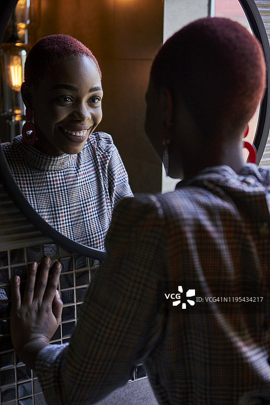 短发年轻女子看着圆形镜子中的自己并微笑图片素材