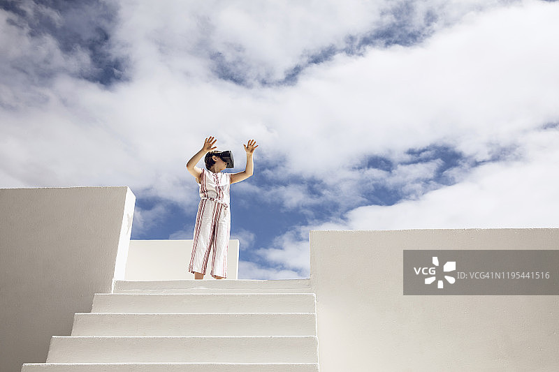 女孩站在楼梯顶端，戴着VR眼镜观看图片素材