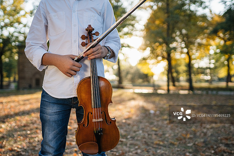 儿童站在公园里拿着小提琴和弓图片素材