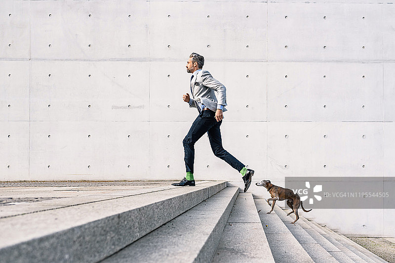 在户外与狗一同奔跑的商人图片素材