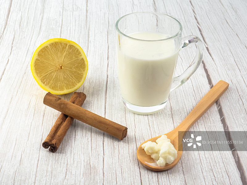 木勺中的开菲尔菌、玻璃杯中的全脂牛奶、肉桂棒和柠檬图片素材