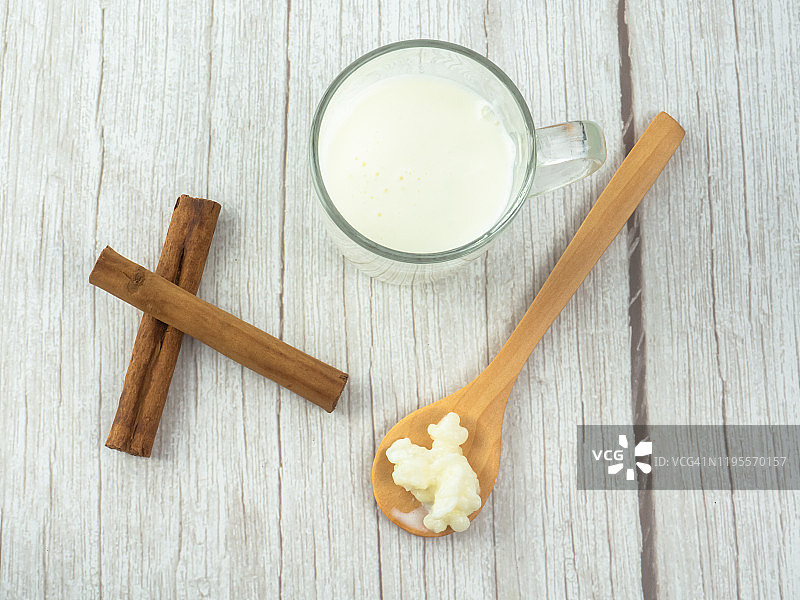 木勺中的开菲尔菌和玻璃杯中的全脂牛奶及肉桂棒图片素材